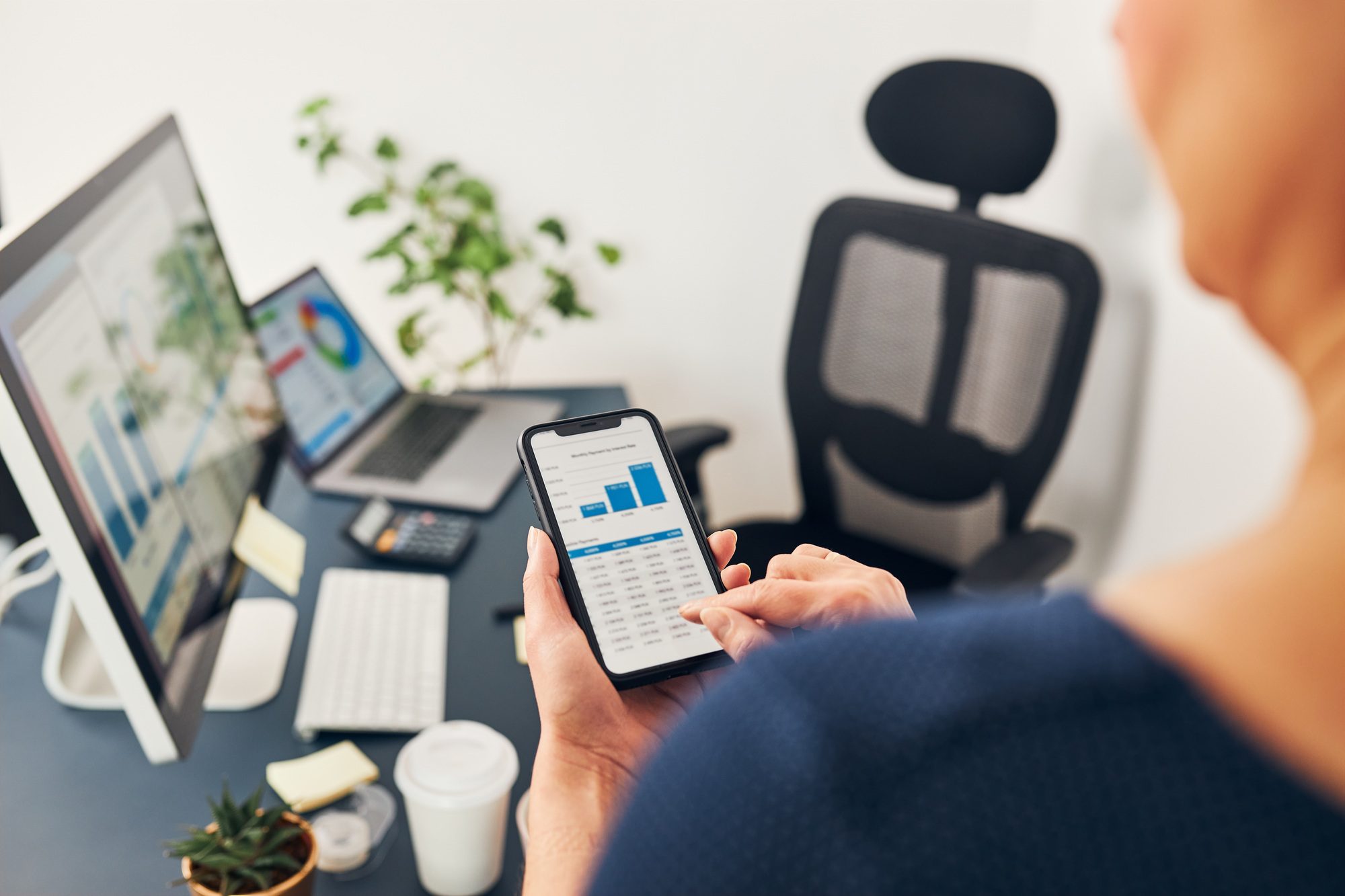 Businesswoman working with financial data on charts and tables on smartphone and computer