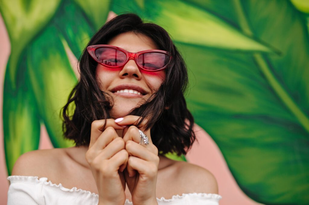 Sorgloses Model mit pinker Sonnenbrille posiert vor Graffiti