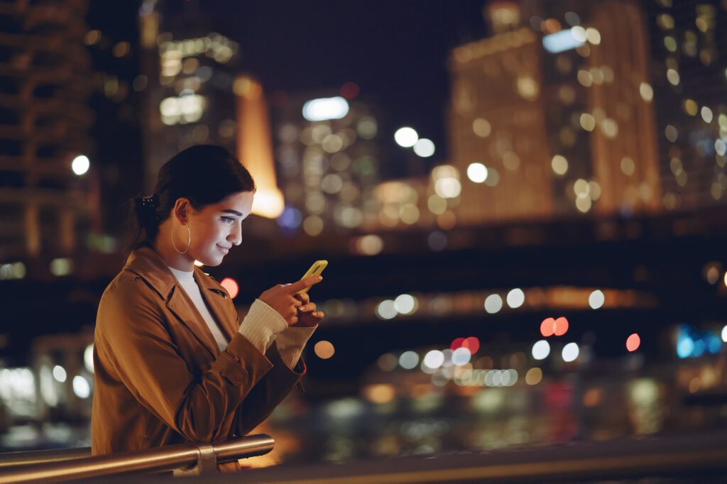 Mädchen nachts mit leuchtendem Smartphone im Gesicht