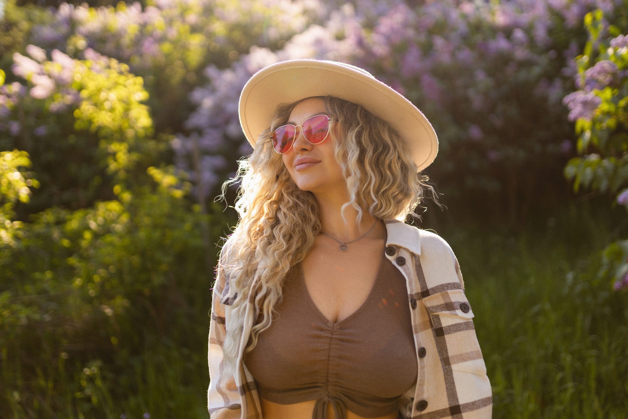 Optics for vision and fashion. Sexy curly blonde looking at the camera wearing glasses and a hat on