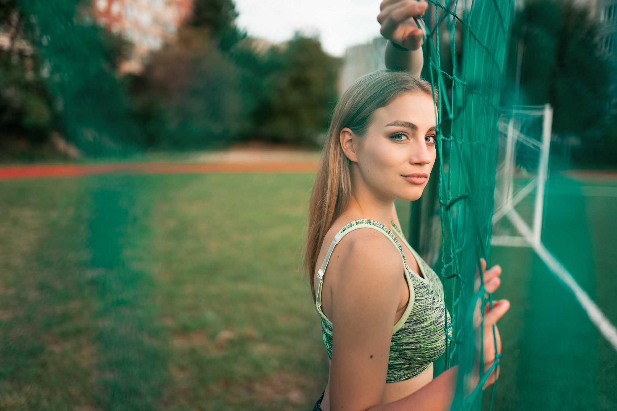 Portrait of a beautiful sports girl with beautiful eyes who stands behind the net of the goal