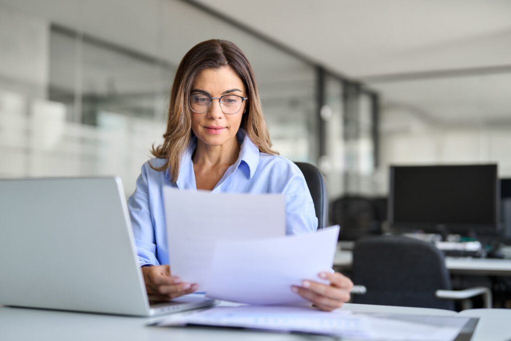 Professionelles OnlyFans Management: Geschäftsfrau prüft Dokumente am Laptop